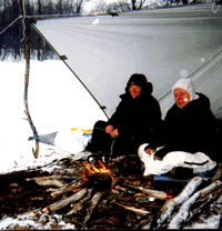 Gail Bosio and Mary Powell enjoy a small fire under a tarp shelter