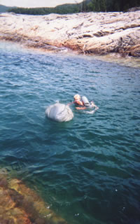 Mary Powell swims across a deep channel with her pack